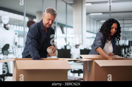 Struggling Workers Watch As AI Robots Take Over Their Jobs. Unemployed Workers Pack Boxes After Being Replaced Stock Photo
