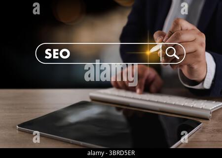 A seo search engine optimization business person using digital device to search for seo strategies with search bar overlay showing word seo Stock Photo