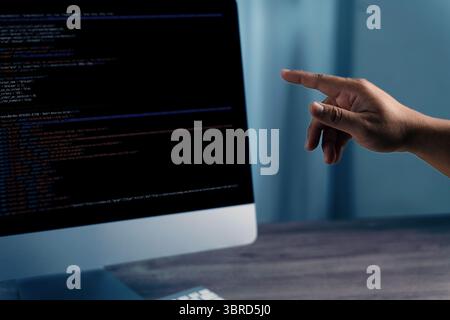 A programming code on representing person pointing computer screen displaying code, indicating programming or software development activity Stock Photo