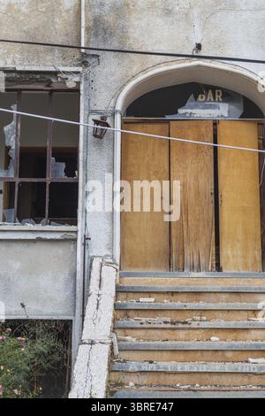 View of a decaying building, windows shattered and boarded doors stand as silent witnesses to time's passage, in Varosha, Famagusta, Cyprus. Stock Photo