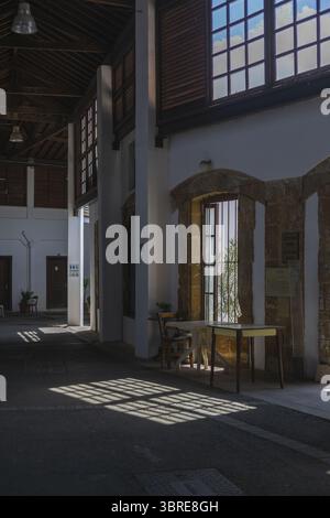Lefkosia, Cyprus - 25 June 2025: View of sun-drenched interior space, casting shadows across the floor, contrasting with the white walls and dark wood beams, highlighting the architectural details. Stock Photo