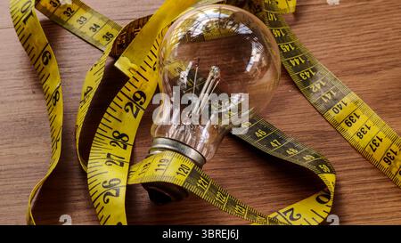 Light Bulb and Measuring Tape on Wooden Table Stock Photo