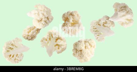 Fresh cauliflower florets falling on light green background Stock Photo