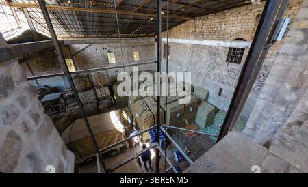Aerial view of a warehouse interior with stacked green soap bars, stone walls, and a metal roof. Storage area for soap curing. Aleppo, Syria Stock Photo