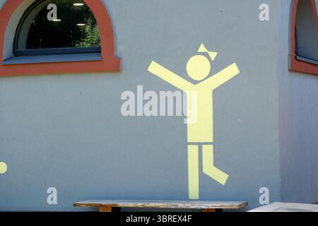 A playful mural depicting a cheerful figure dances on a gray wall, brightening the area. Stock Photo
