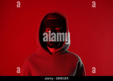 Anonymity. Woman wearing mask on red background Stock Photo