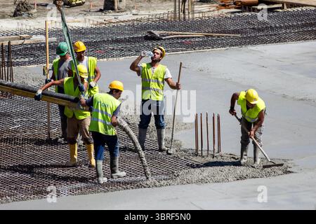Construction crew pouring reinforced concrete for building footings at a commercial or residential development site. Antwerp, Belgium - Jul 9, 2013 Stock Photo