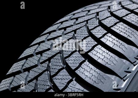 Close-up of a modern car tire with detailed tread pattern, isolated on a black background Stock Photo