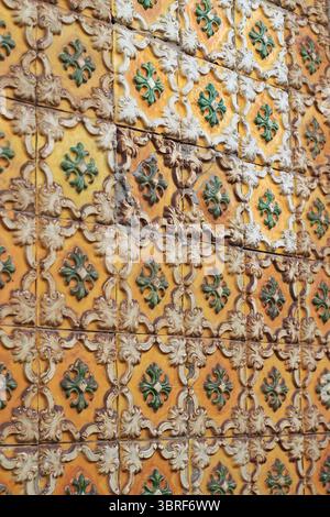 Vintage Portuguese azulejo tile pattern with diamond shapes in ochre and green. Worn ceramic wall surface from an old building. Ideal for culture, arc Stock Photo