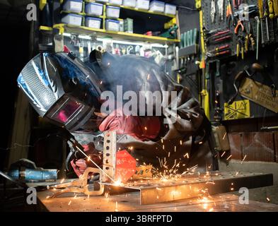 Worker with protective mask welding metal in workshop Stock Photo