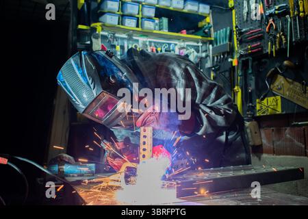 Worker with protective mask welding metal in workshop Stock Photo