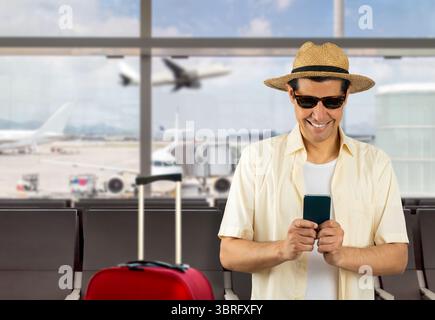 Man texting using smartphone at airport with a happy face standing and smiling with a confident smile showing teeth Stock Photo