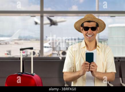 Man texting using smartphone at airport with a happy face sitting and looking at camera with a confident smile showing teeth Stock Photo