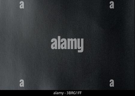 Close-up of a smooth paper, dark surface showcases subtle variations, perfect for minimalist aesthetics or artistic projects. Stock Photo
