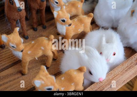 Delicate handmade animals rest together in a wooden crate under warm light. Stock Photo