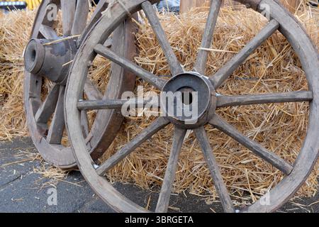 Old wooden wheels lean against a straw bale on a crisp fall day. Stock Photo