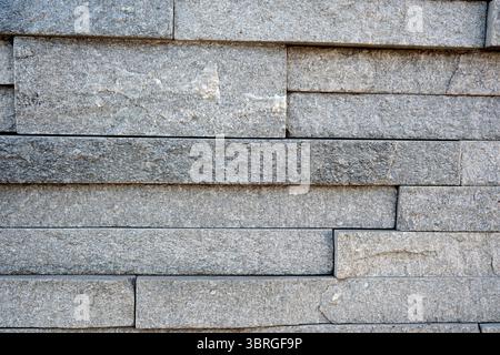 Gray stone blocks create a striking textured wall surface in daylight. Stock Photo