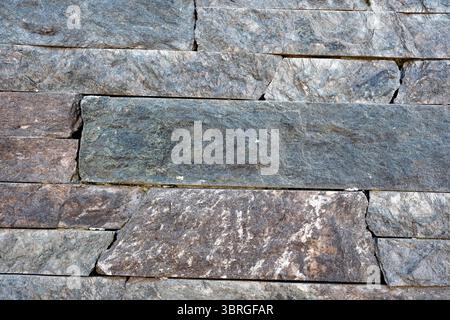 Close-up of a textured stone wall showcasing diverse colors in light. Stock Photo