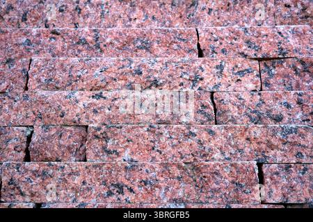 Stacks of pink granite bricks create an elegant and textured display. Stock Photo