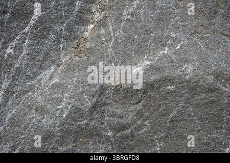 Veins of gray and white intertwine across the rock's rugged texture. Stock Photo