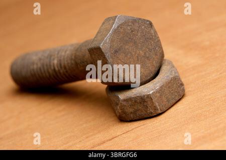 Rusty bolts and nuts artfully arranged on a wooden table. Stock Photo