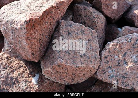 Richly colored granite rocks lie scattered under the warm sunlight. Stock Photo