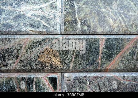 Close-up view of a textured stone wall displaying vivid mineral patterns. Stock Photo
