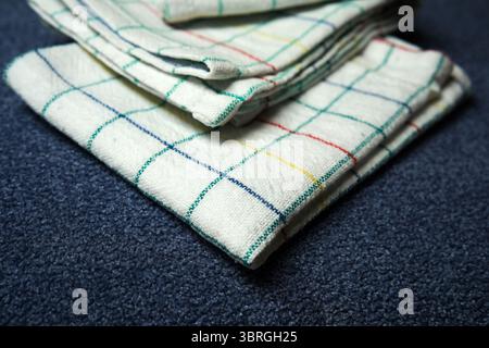Soft checkered fabrics are neatly folded on a deep blue backdrop. Stock Photo