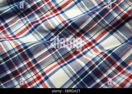 Softly draping fabric showcases a vibrant plaid pattern in rich colors. Stock Photo