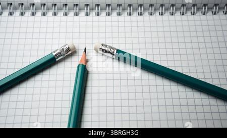 Teal pencils are artistically placed on a grid-patterned notebook. Stock Photo