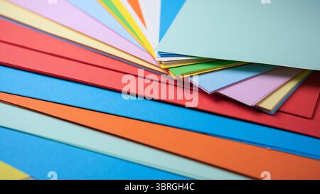 Brightly colored sheets of paper are artfully arranged in a creative setting. Stock Photo