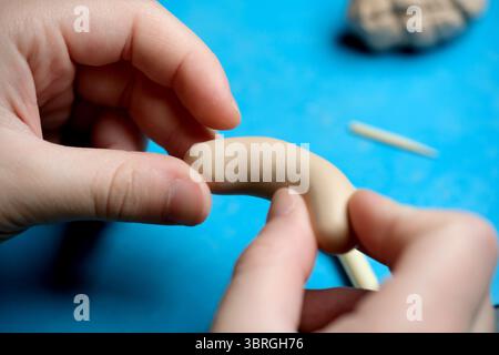 Hands mold clay into a playful design, showcasing creativity. Stock Photo