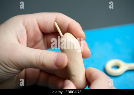 Hands mold soft clay into a creative shape at a workspace with tools. Stock Photo