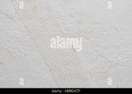 Plastic covering mesh band for even plastering on a white grungy wall, abstract textured construction Stock Photo