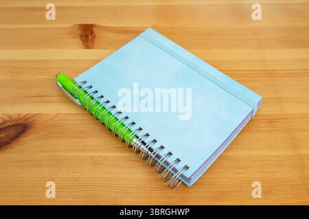 Bright blue hard cover notebook binded with a metal spring spiral on a wooden desktop Stock Photo