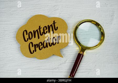 Content Creator text on sticky note with magnifying glass on concrete background Stock Photo