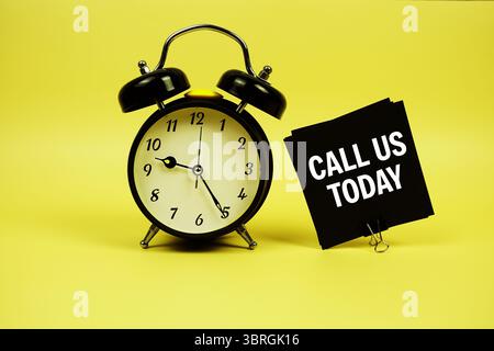 Call Us Today text message on sticky note with alarm clock on yellow background Stock Photo
