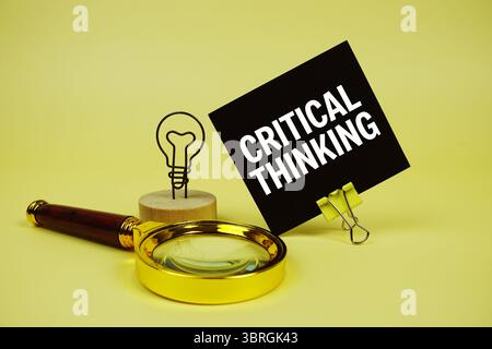 Critical Thinking text message on sticky note with magnifying glass on yellow background Stock Photo