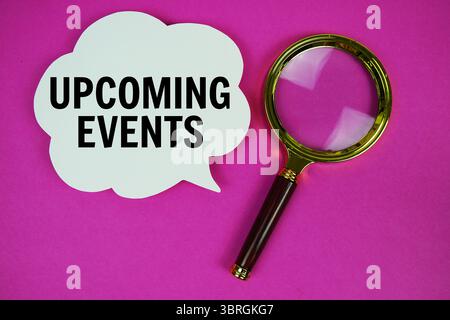 Upcoming Events text with speech bubble and magnifying glass on pink background Stock Photo
