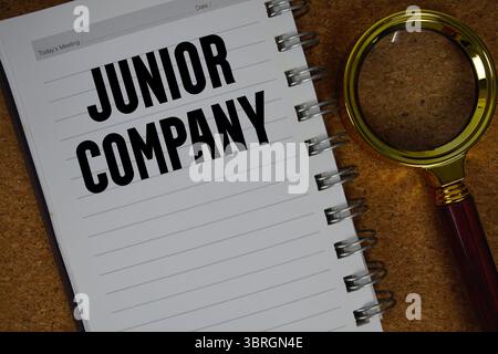 Junior Company text written on notebook paper with magnifying glass Stock Photo