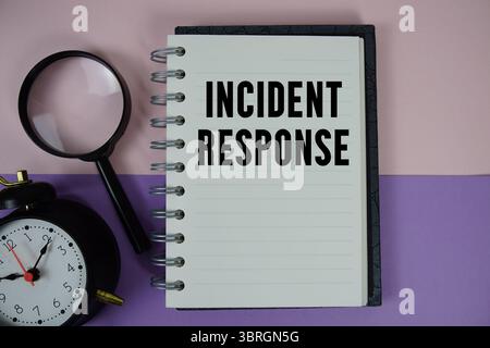 Incident Response text written on notebook paper with magnifying glass and alarm clock Stock Photo