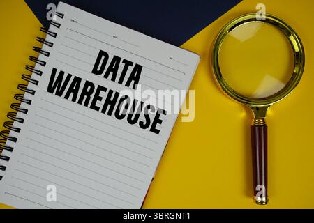 Data Warehouse text with magnifying glass on yellow background Stock Photo