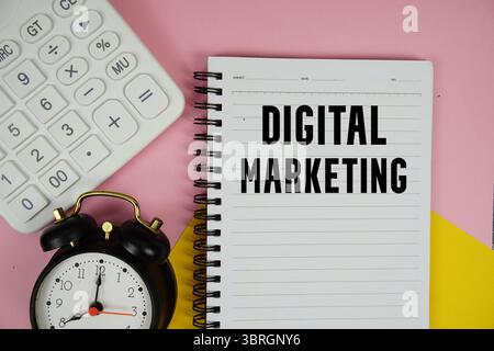 Digital Marketing text written on notepad with calculator and alarm clock on pink background Stock Photo