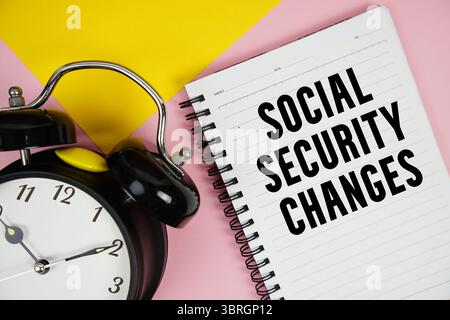 Social Security Changes text written on notepad with alarm clock on pink background Stock Photo