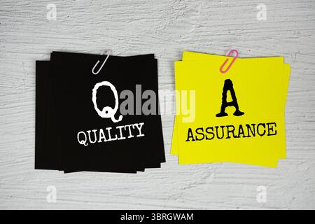 QA - Quality Assurance text on stick note on concrete background Stock Photo
