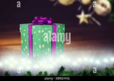 Flat design polka-dotted purple-ribboned gift box is sitting on table, fairy lights and pine branch Stock Photo
