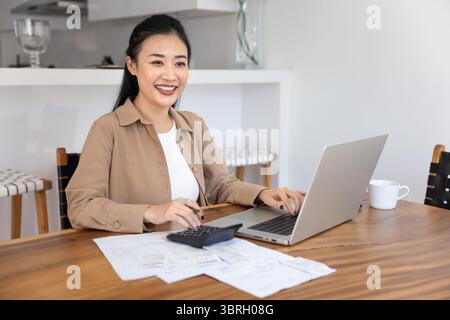 Smiling Asian woman working on financial documents Stock Photo