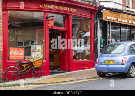 Traditional sweet shop in Scarborough, North Yorkshire, with shopkeeper inside and vintage Coca-Cola advertising, representing British retail heritage Stock Photo