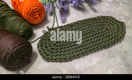 Crochet bag bottom made of green polyester cord. On a gray background. Textured design Stock Photo