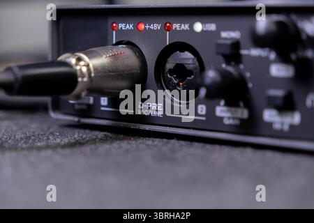 Detailed view of a black audio recording device with an XLR microphone cable plugged in, illustrating essential connectivity and settings for home stu Stock Photo